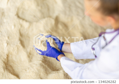 Close-up view of female hands in gloves holding powdered feed Close-up view of female hands in gloves holding powdered feed 134026282