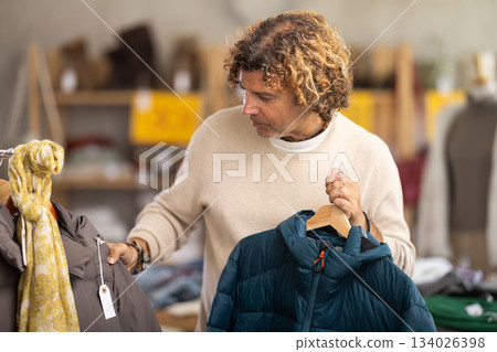 Man search and choose down jacket in store Man search and choose down jacket in store 134026398