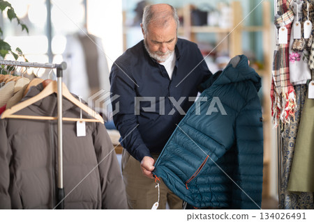 Family clothing store, senior man customer choose down jacket Family clothing store, senior man customer choose down jacket 134026491