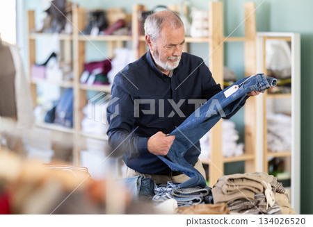 Family clothing store, senior man customer choose jeans Family clothing store, senior man customer choose jeans 134026520