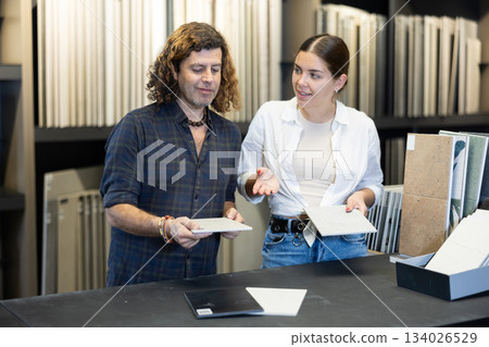 couple in large hardware store chooses ceramic tiles for repair work in kitchen and bathroom 134026529