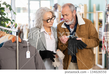 Mature couple spend time in shop and choose gloves 134026550