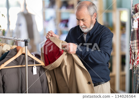 man chooses a brown jacket in a store man chooses a brown jacket in a store 134026564