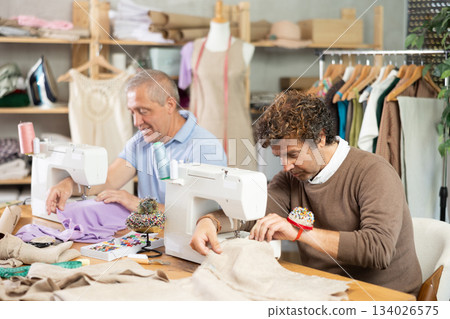 Elderly and adult men tailors sewing on machine 134026575