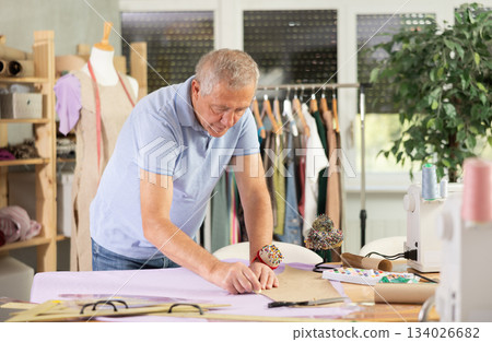 Mature man making markings on paper Mature man making markings on paper 134026682