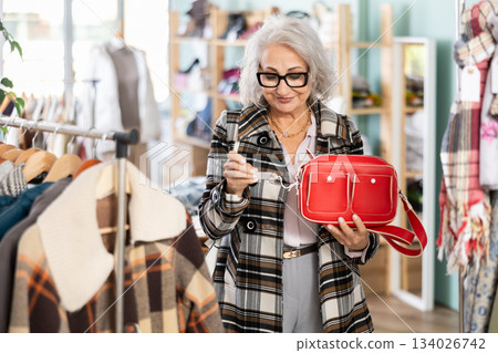 Elderly woman choosing a fashionable handbag in boutique 134026742
