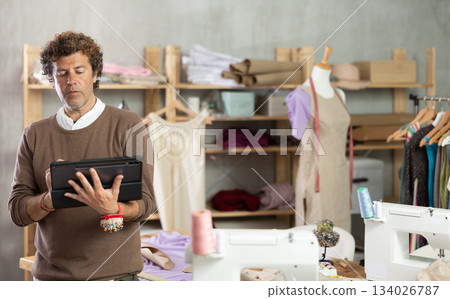 Man tailor creates sketch of dress on tablet 134026787