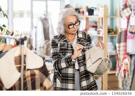 Family clothing store, senior woman customer choose handbag 134026836