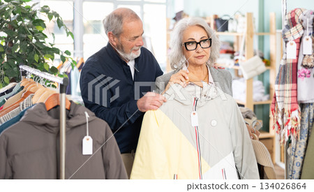 Family clothing store, senior couple customer chooses down jacket 134026864