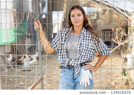 Portrait of happy female farm owner against background of chicken coop Portrait of happy female farm owner against background of chicken coop 134026876