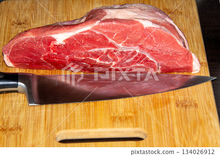 Piece of raw beef on a wooden cutting board. Piece of raw beef on a wooden cutting board. 134026912