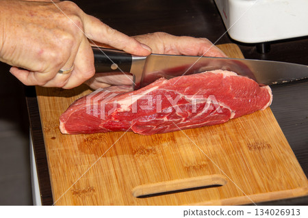Piece of raw beef on a wooden cutting board. Piece of raw beef on a wooden cutting board. 134026913