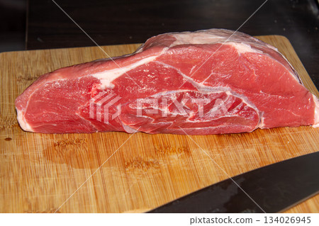 Piece of raw beef on a wooden cutting board. 134026945