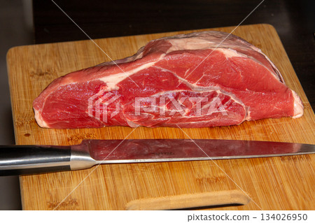 Piece of raw beef on a wooden cutting board. 134026950