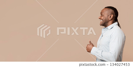 Approval concept. Positive middle aged african american man gesturing thumb up, looking at copy space, orange background Approval concept. Positive middle aged african american man gesturing thumb up, looking at copy space, orange background 134027453