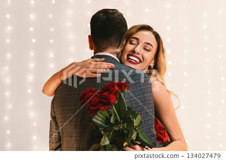 Happy Anniversary. Pleased Young Woman Holding Red Roses Bouquet And Embracing Boyfriend, Standing With Closed Eyes, Grateful For Surprise, Free Space Happy Anniversary. Pleased Young Woman Holding Red Roses Bouquet And Embracing Boyfriend, Standing With Closed Eyes, Grateful For Surprise, Free Space 134027479