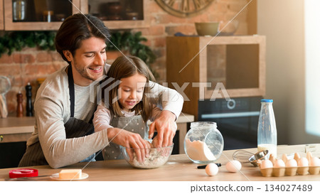 Father and daughter making pastry in kitchen together, kneading daugh in bowl, free space Father and daughter making pastry in kitchen together, kneading daugh in bowl, free space 134027489