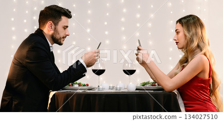 Modern Date Concept. Man And Woman Spending Time With Their Phones, Ignoring Each Other On Romantic Date In Restaurant, Side View 134027510