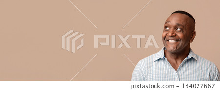Wow. Positive middle aged african man looking aside at empty space, orange background, panorama Wow. Positive middle aged african man looking aside at empty space, orange background, panorama 134027667