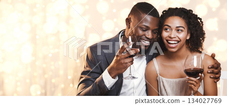 Portrait of happy young african couple celebrating St. Valentine's Day at restaurant, drinking red wine, man hugging woman, close up 134027769