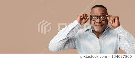 What is there. Middle aged afro man looking at camera through glasses, orange background What is there. Middle aged afro man looking at camera through glasses, orange background 134027800