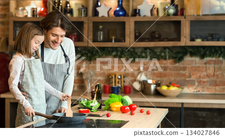 Dad teaching his cute daughter how to cook food on pan, preparring healthy lunch together, free space 134027846