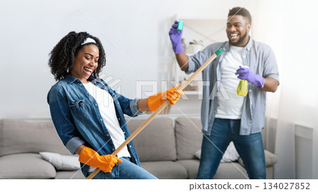 Spring-Cleaning With Fun. Joyful African American Couple Fooling Together While Tidying Their Apartment, Selective Focus On Woman 134027852