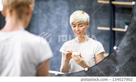 Skin Care Concept. Woman Holding Cosmetic Cream Caring For Facial Skin Preventing Wrinkles At Home. Selective Focus 134027902
