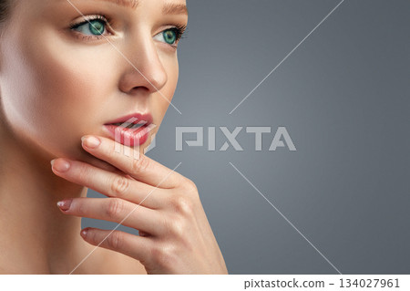 Facial Skincare. Pretty Young Woman With Perfect Makeup Posing Touching Chin And Looking Aside At Free Space For Text Over Gray Studio Background. Panorama, Cropped 134027961