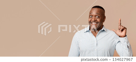 Great idea. Cheerful middle aged african man pointing his finger up with inspiration, orange background Great idea. Cheerful middle aged african man pointing his finger up with inspiration, orange background 134027967
