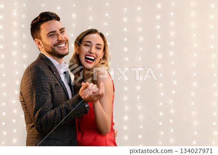 Party For Two. Joyful Young Couple Dancing, Holding Hands And Sincerely Laughing While Posing Over Beige Background With Bokeh, Panorama Party For Two. Joyful Young Couple Dancing, Holding Hands And Sincerely Laughing While Posing Over Beige Background With Bokeh, Panorama 134027971