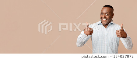 I like it. Enthusiastic mature afro american man gesturing thumbs up with both hands, orange background 134027972
