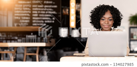 Black young woman freelancer working with laptop, sitting at cafe, copy space Black young woman freelancer working with laptop, sitting at cafe, copy space 134027985