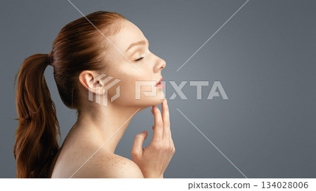 Female Beauty Portrait. Side View Of Sensual Shirtless Ginger-Haired Young Lady With Ponytail Hairstyle Posing Touching Chin With Eyes Closed Over White Background. Studio Shot 134028006
