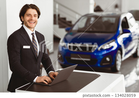 Car Sales Manager Working On Laptop, Standing At Desk In Luxury Dealership Office. Selective Focus, Free Space Car Sales Manager Working On Laptop, Standing At Desk In Luxury Dealership Office. Selective Focus, Free Space 134028059