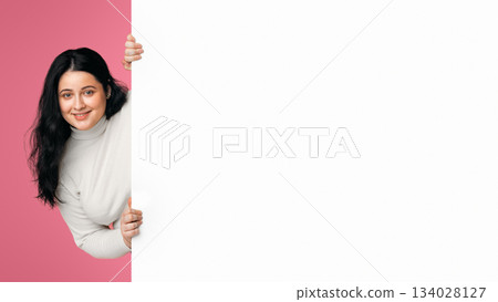 Smiling plump girl holding big white advertisement board with free space for your text, standing over pink background Smiling plump girl holding big white advertisement board with free space for your text, standing over pink background 134028127