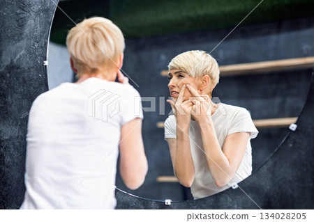 Middle-Aged Lady Having Acne Problem Squeezing Pimple On Face Standing In Bathroom At Home. Selective Focus 134028205