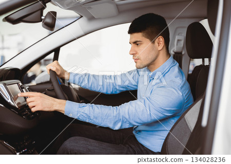 Transport, Destination, Modern Technology Concept. Man searching for route using navigation system on car dashboard screen Transport, Destination, Modern Technology Concept. Man searching for route using navigation system on car dashboard screen 134028236