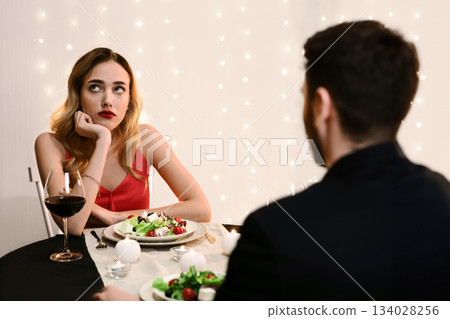 Unsuccessful Date. Young woman feeling bored at dinner in restaurant, looking away with disappointed face expression, selective focus Unsuccessful Date. Young woman feeling bored at dinner in restaurant, looking away with disappointed face expression, selective focus 134028256
