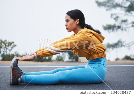 Sports, leg stretching and woman runner doing exercise on a outdoor road feeling serious. Workout, running training and wellness warm up of young female ready for sports and marathon run in mist 134028427