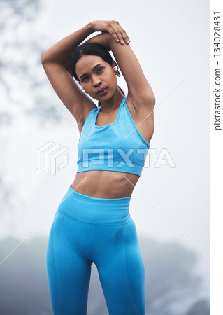 Fitness arm stretching, woman and runner exercise on a outdoor road in the mountains breathing. Workout, running training and wellness of a young female ready for sports and marathon run in mist 134028431