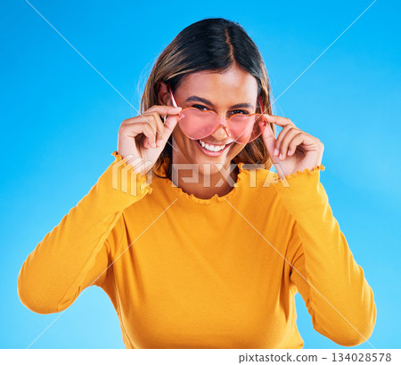 Fashion portrait, heart sunglasses and woman smile with casual spring clothes, designer brand glasses or outfit style. Gen z aesthetic, trendy face and young female model on blue background studio Fashion portrait, heart sunglasses and woman smile with casual spring clothes, designer brand glasses or outfit style. Gen z aesthetic, trendy face and young female model on blue background studio 134028578