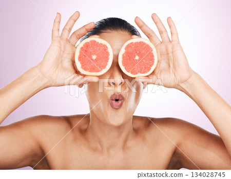 Face kiss, grapefruit and skincare of woman in studio isolated on a purple background. Natural cosmetics, food and female model with fruit for vitamin c, nutrition or healthy diet, wellness or beauty 134028745