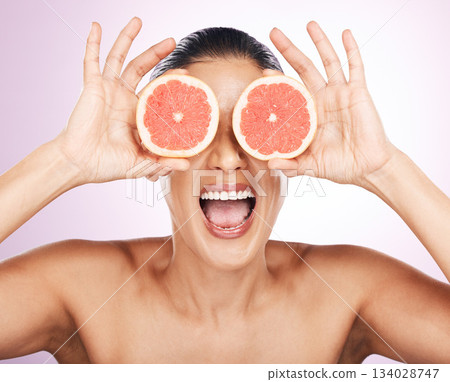 Face laughing, grapefruit and skincare of woman in studio isolated on a purple background. Natural cosmetics, food and happy mature female model with fruit for vitamin c, nutrition and healthy diet. 134028747