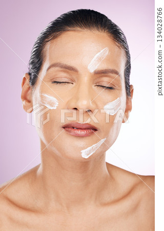 Face, cream and skincare of woman with eyes closed in studio isolated on a purple background. Mature, cosmetics and female with dermatology lotion, creme or moisturizer for healthy skin or anti aging Face, cream and skincare of woman with eyes closed in studio isolated on a purple background. Mature, cosmetics and female with dermatology lotion, creme or moisturizer for healthy skin or anti aging 134028766
