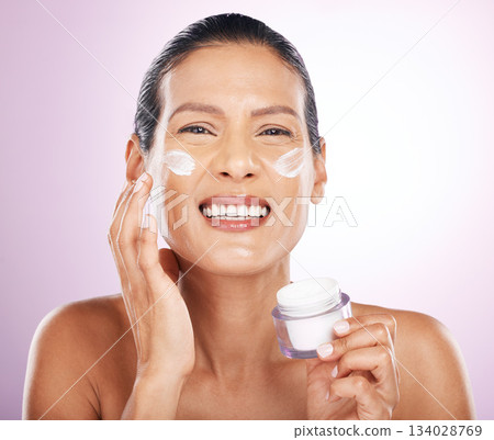 Face, cream jar and skincare of woman in studio isolated on a purple background. Mature, portrait and happy female model with dermatology lotion, creme and moisturizer cosmetics for healthy skin. Face, cream jar and skincare of woman in studio isolated on a purple background. Mature, portrait and happy female model with dermatology lotion, creme and moisturizer cosmetics for healthy skin. 134028769