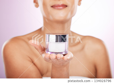 Hands, cream jar and skincare of woman in studio isolated on a purple background. Face, dermatology cosmetics and female model holding lotion container, creme or moisturizer product for skin health. 134028796