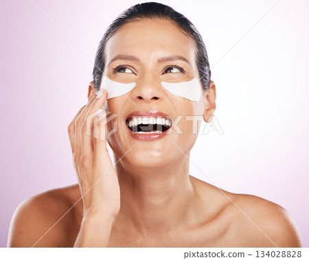Laughing, skincare and woman eye patches in studio isolated on purple background. Thinking, dermatology cosmetics or funny, face and mature female model with facial mask for anti aging or collagen. Laughing, skincare and woman eye patches in studio isolated on purple background. Thinking, dermatology cosmetics or funny, face and mature female model with facial mask for anti aging or collagen. 134028828