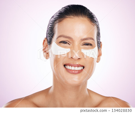 Face, skincare and woman with eye patches in studio isolated on a purple background. Dermatology portrait, cosmetics and happy, mature and female smile with facial mask for collagen and anti aging. Face, skincare and woman with eye patches in studio isolated on a purple background. Dermatology portrait, cosmetics and happy, mature and female smile with facial mask for collagen and anti aging. 134028830