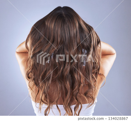 Woman, beauty and hair in studio for curls, growth and healthy shine on blue background. Aesthetic female model back for haircare, self care and cosmetic results for salon or hairdresser treatment Woman, beauty and hair in studio for curls, growth and healthy shine on blue background. Aesthetic female model back for haircare, self care and cosmetic results for salon or hairdresser treatment 134028867